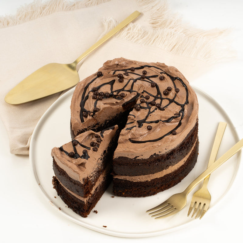 Slice of chocolate cake with layers of light sponge and creamy buttercream.