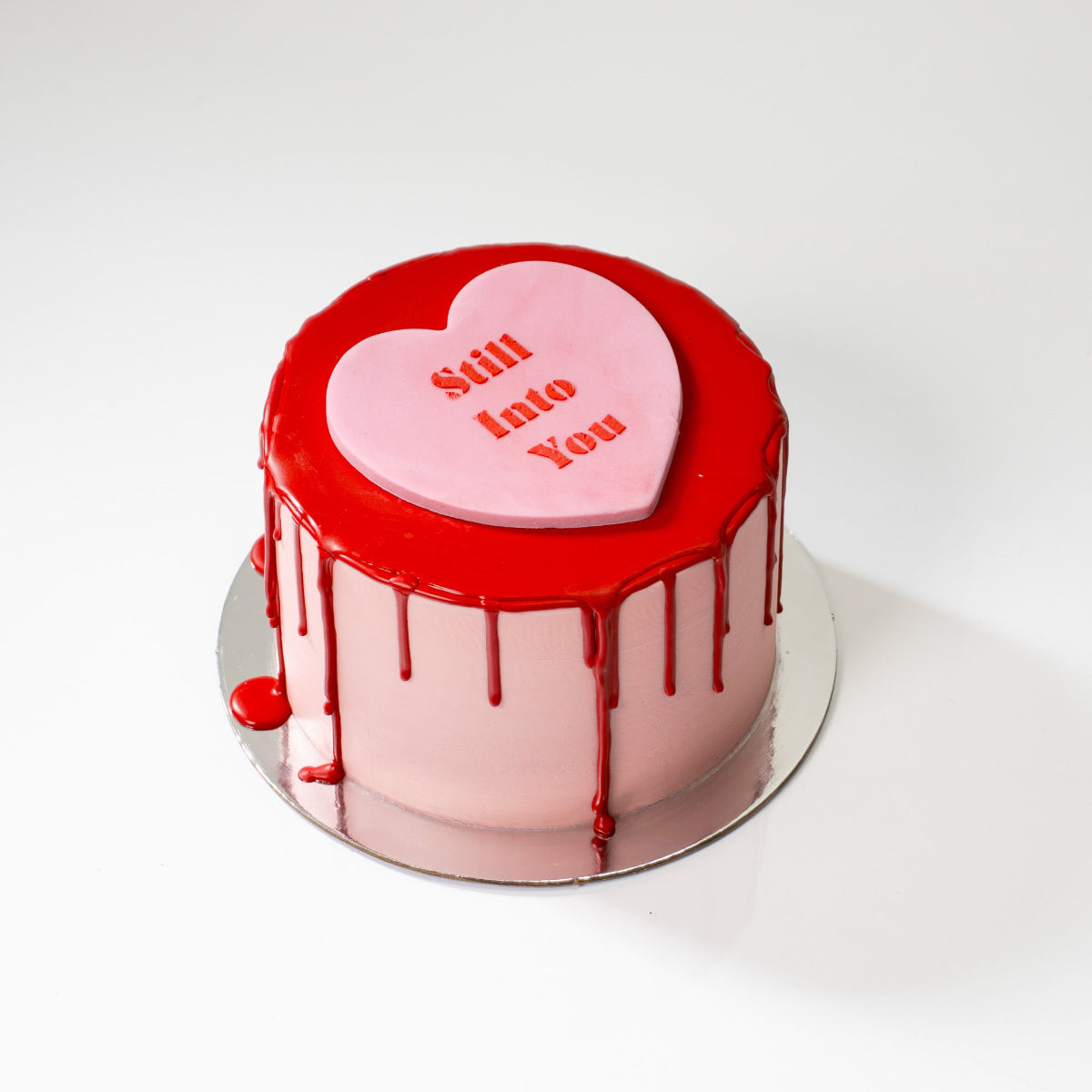 Valentine’s heart-shaped chocolate cake with pink icing, red chocolate drip and fondant heart on top