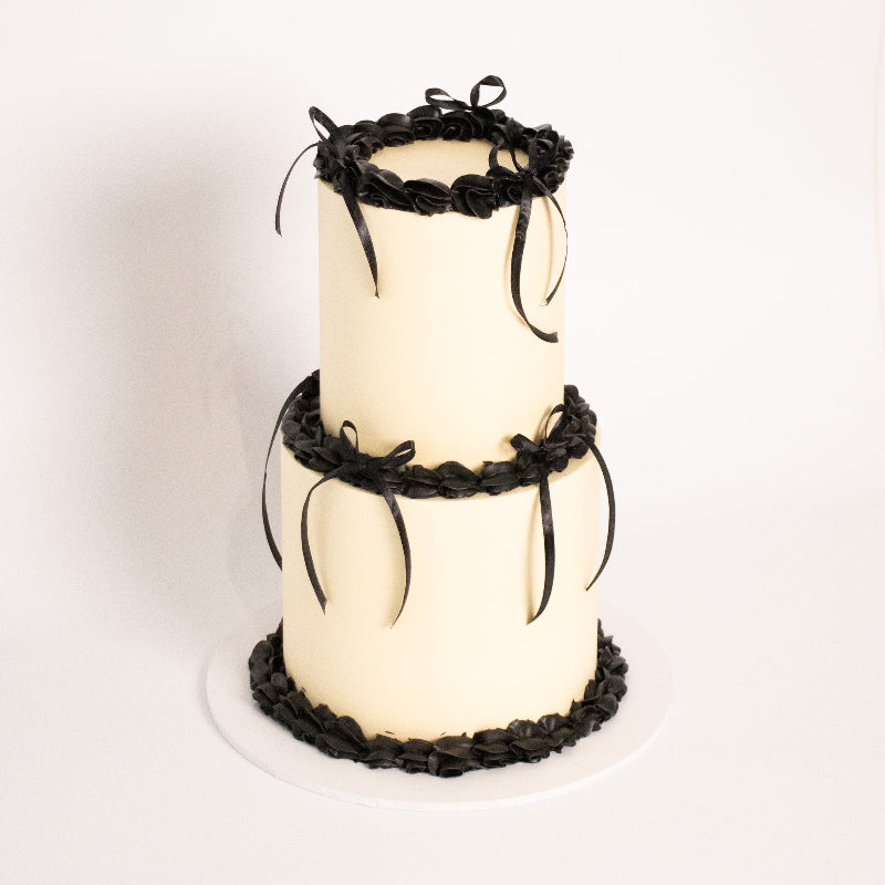 Two-tier vintage cake with ornate piping and ribbon details.