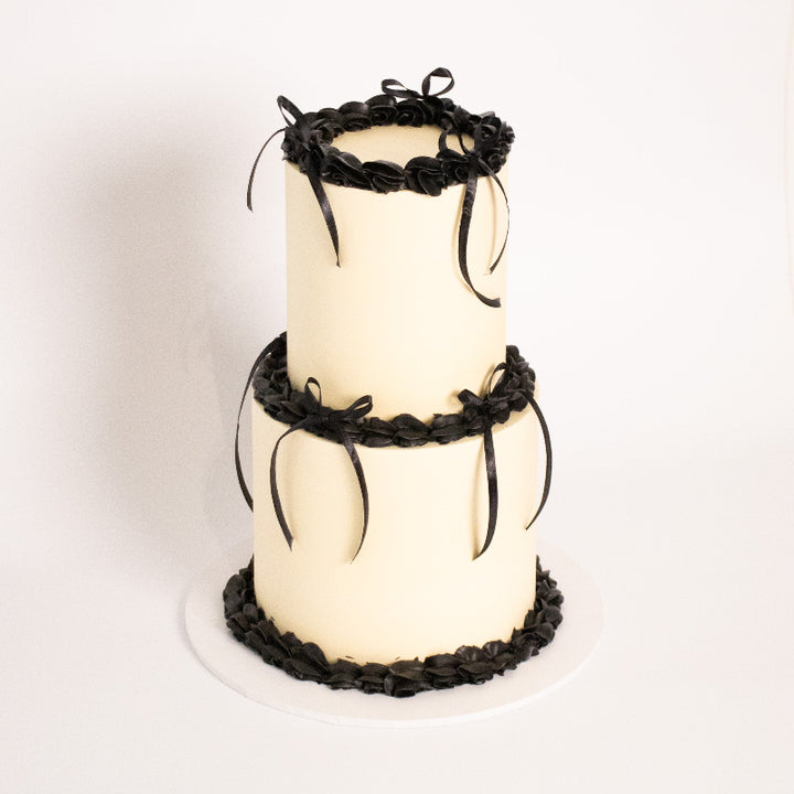 Two-tier vintage cake with ornate piping and ribbon details.