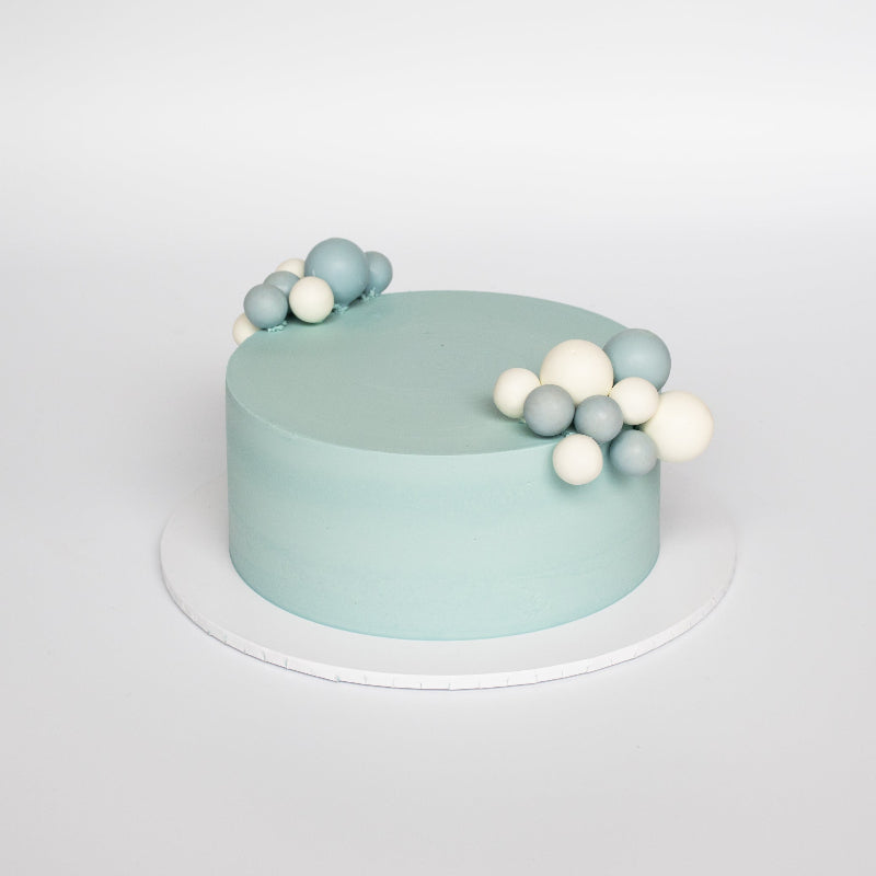Elegant buttercream cake topped with bubble decorations in pastel tones.