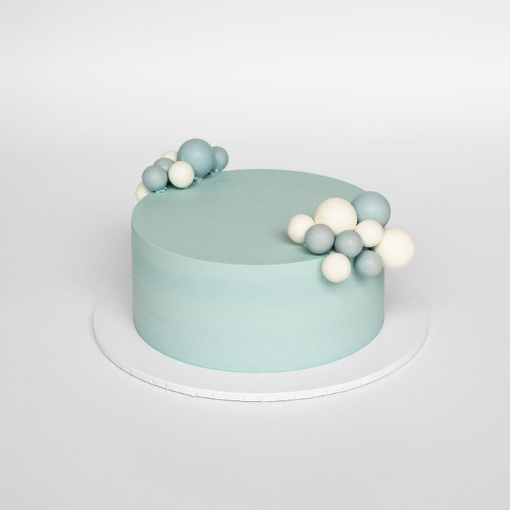 Elegant buttercream cake topped with bubble decorations in pastel tones.