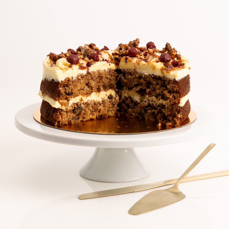 Slice of spiced carrot cake with cream cheese frosting and caramel drizzle.