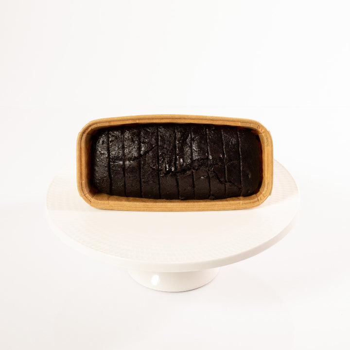 Moist vegan chocolate loaf cake topped with glossy chocolate glaze.