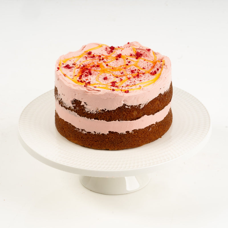 Whole lemon and raspberry cake topped with buttercream and fruit.