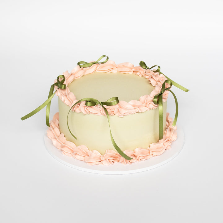 Vintage custom cake with piped borders, bows, and pastel icing.